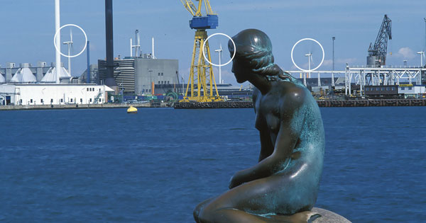 Figure 15-50 on page 371 of Wind Energy for the Rest of Us illustrating the compatability of wind turbines with tourist destinations. Copenhagen's Little Mermaid in the foreground. Lynetten wind cooperative in the background.
